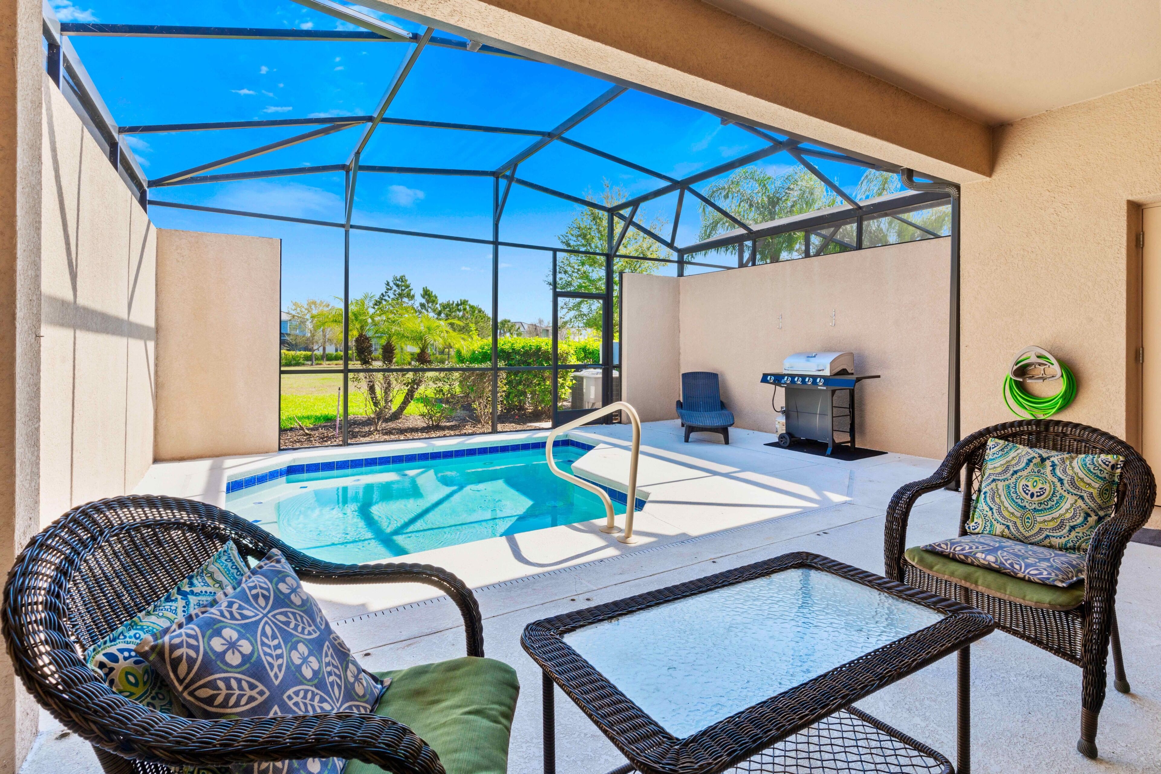 Un espace extérieur abrité avec une piscine, des meubles en osier et un barbecue.