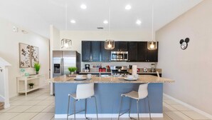 A modern kitchen with a central island, stainless steel appliances, and pendant lighting. - 4722 Terrasonesta Drive (Davenport)