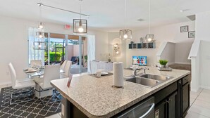 A modern kitchen with granite countertops, stainless steel appliances, and pendant lighting. - 4722 Terrasonesta Drive (Davenport)
