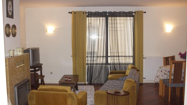 Una sala de estar con un conjunto de sofás, un televisor y una mesita.