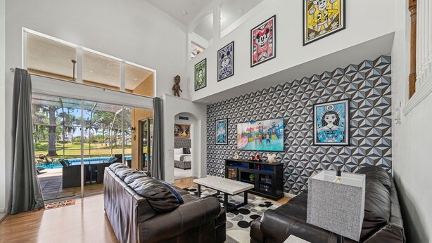 Uma sala de estar moderna com vista para a piscina, um sofá seccional, uma mesa de centro e uma televisão.