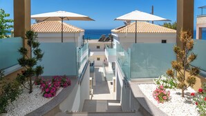 A hotel corridor with a view of the sea, white pebbles, and small trees. - Vrachos Luxury Maisonettes (Parga)