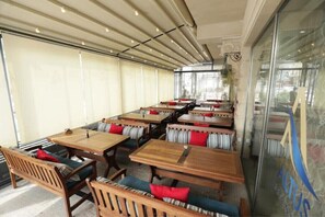 Un restaurante con varias mesas y bancos de madera, algunos con cojines rojos.