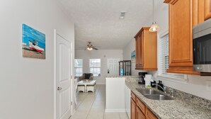 A kitchen with granite countertops, wooden cabinets, a ceiling fan, and a dining area with a table and chairs.