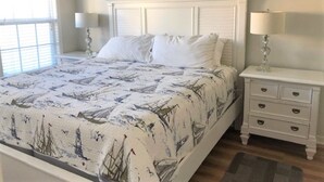 A bedroom with a bed, nightstands, and a window.