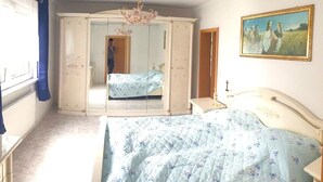 A bedroom with a bed, a wardrobe, a mirror, and a painting on the wall. - Ferienhaus in Barenstein bei Grunen Hugeln (Baerenstein)