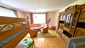 A room with bunk beds, a sofa, a television, and a cabinet. - Ferienhaus in Barenstein bei Grunen Hugeln (Baerenstein)