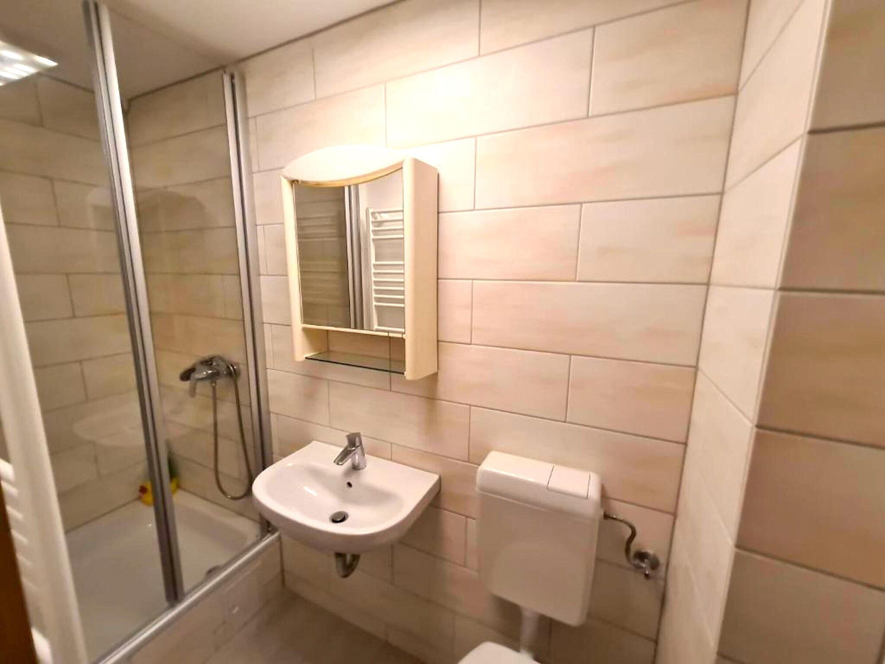 Ein Badezimmer mit Glasdusche, Waschbecken und Toilette.