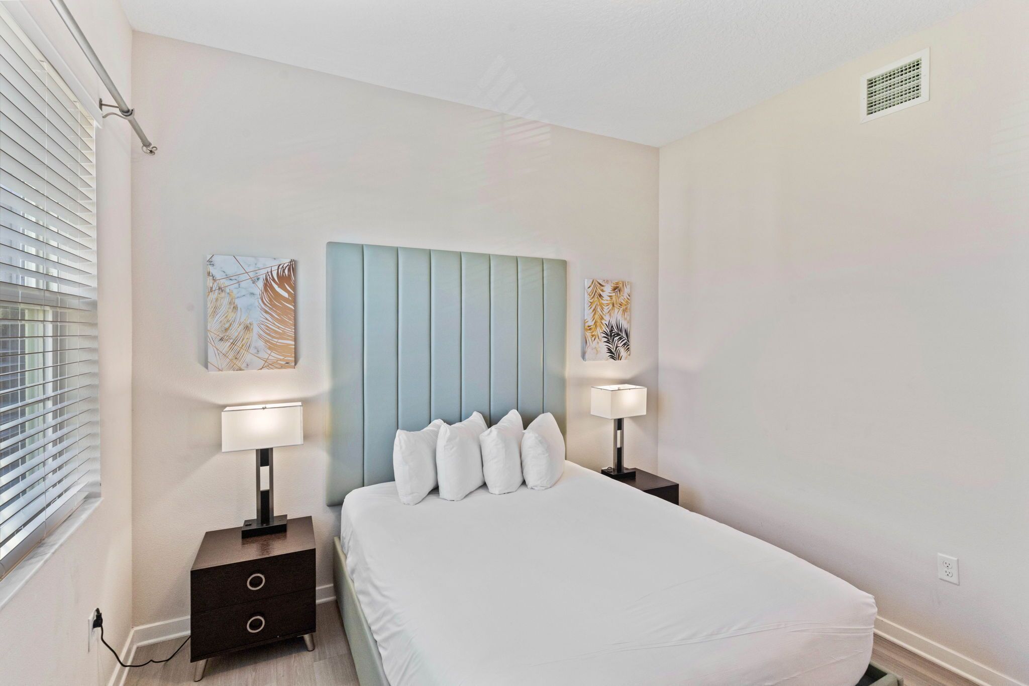 A bedroom with a bed, two bedside tables, and wall art.