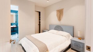 Une chambre moderne avec un grand lit, des tables de chevet et une décoration murale en macramé.