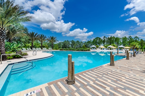 Relax by the pool surrounded by lush greenery and palm trees.