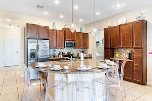Enjoy cooking in this well-equipped kitchen with a central island, stainless steel refrigerator, microwave, and wooden cabinets.