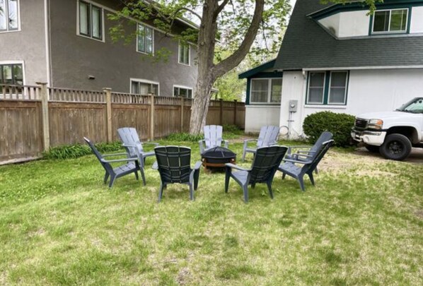 A backyard with a fire pit and four Adirondack chairs. - Cobblestone Cottage, 4 Bedroom, centrally located (La Crosse)