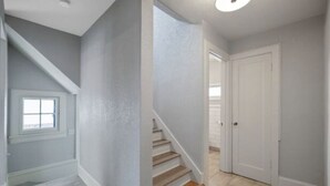 A hallway with a staircase leading to a door. - Cobblestone Cottage, 4 Bedroom, centrally located (La Crosse)