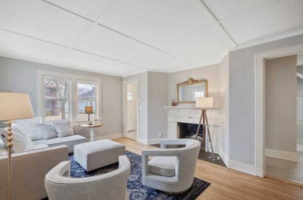 A modern living room with a fireplace, a sofa, a coffee table, and a lamp.