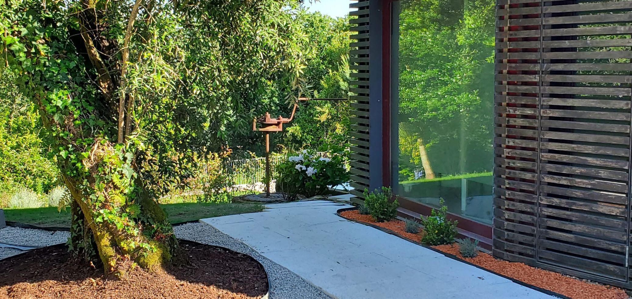 Un bâtiment moderne avec un chemin en béton menant à une terrasse en bois.
