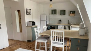 Una cucina compatta con zona pranzo, pavimento in legno e un piccolo tavolo.