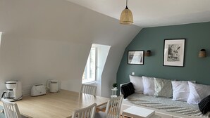 Una stanza moderna e luminosa, con un tavolo da pranzo, sedie, un letto con copriletto decorato e un lampadario.