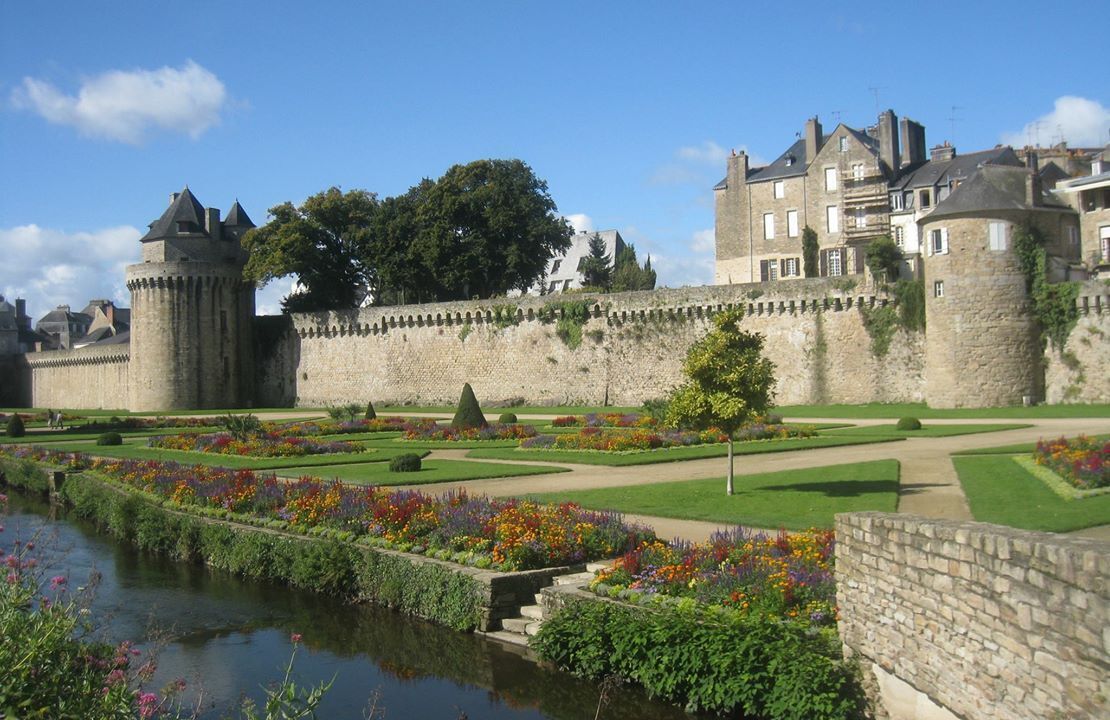 Un château historique doté d’un fossé, de jardins à la française et d’un grand mur de pierre.