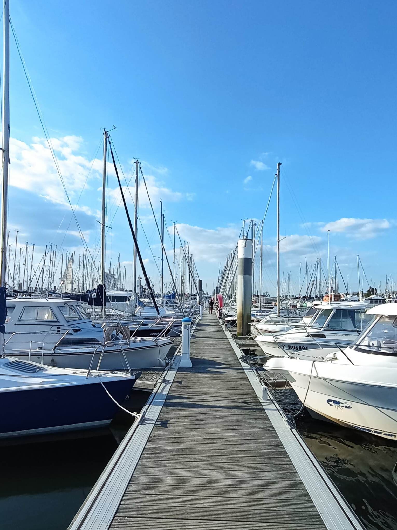 A marina with numerous boats docked along a wooden walkway.