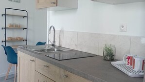 A modern kitchen with wooden cabinets, a stainless steel sink, and a built-in range hood. - LE Kevav - A 300 M DE LA Cote (Locmiquélic)