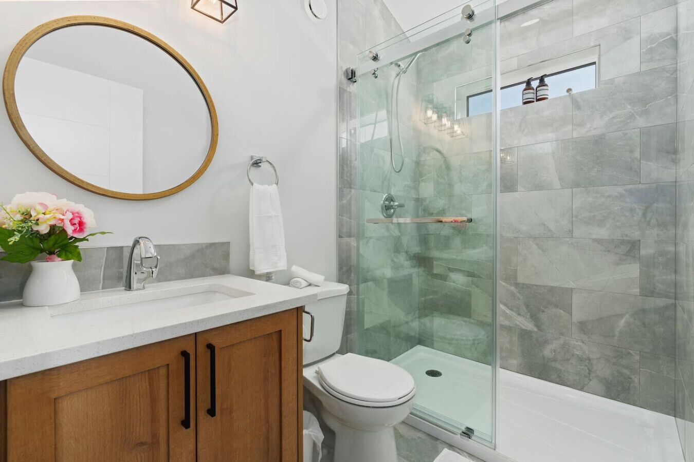 Une salle de bain moderne avec une douche à parois de verre, des toilettes blanches et un meuble-lavabo en bois avec un évier.