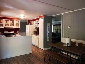 Enjoy meals in the kitchen adjacent to a dining area with a wooden table and benches.