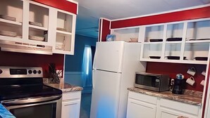 A compact kitchen with white cabinets, a stainless steel oven, a microwave, and a refrigerator. - Near The Lake (Bee Branch)
