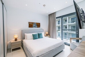 Una camera da letto moderna con un letto grande, due comodini con lampade, una finestra con tende e vista sulla città.