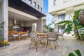 Un'area patio esterna con tavolo e sedie, angolo cottura e vista sulla facciata dell'edificio.