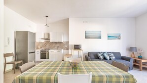 Une cuisine moderne avec des meubles blancs, un four à micro-ondes et un coin repas agrémenté d’une nappe à carreaux.