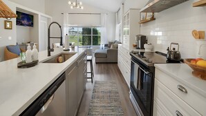 Une cuisine moderne dotée d’un îlot central, d’un coin repas avec un canapé et d’une vue sur l’extérieur.