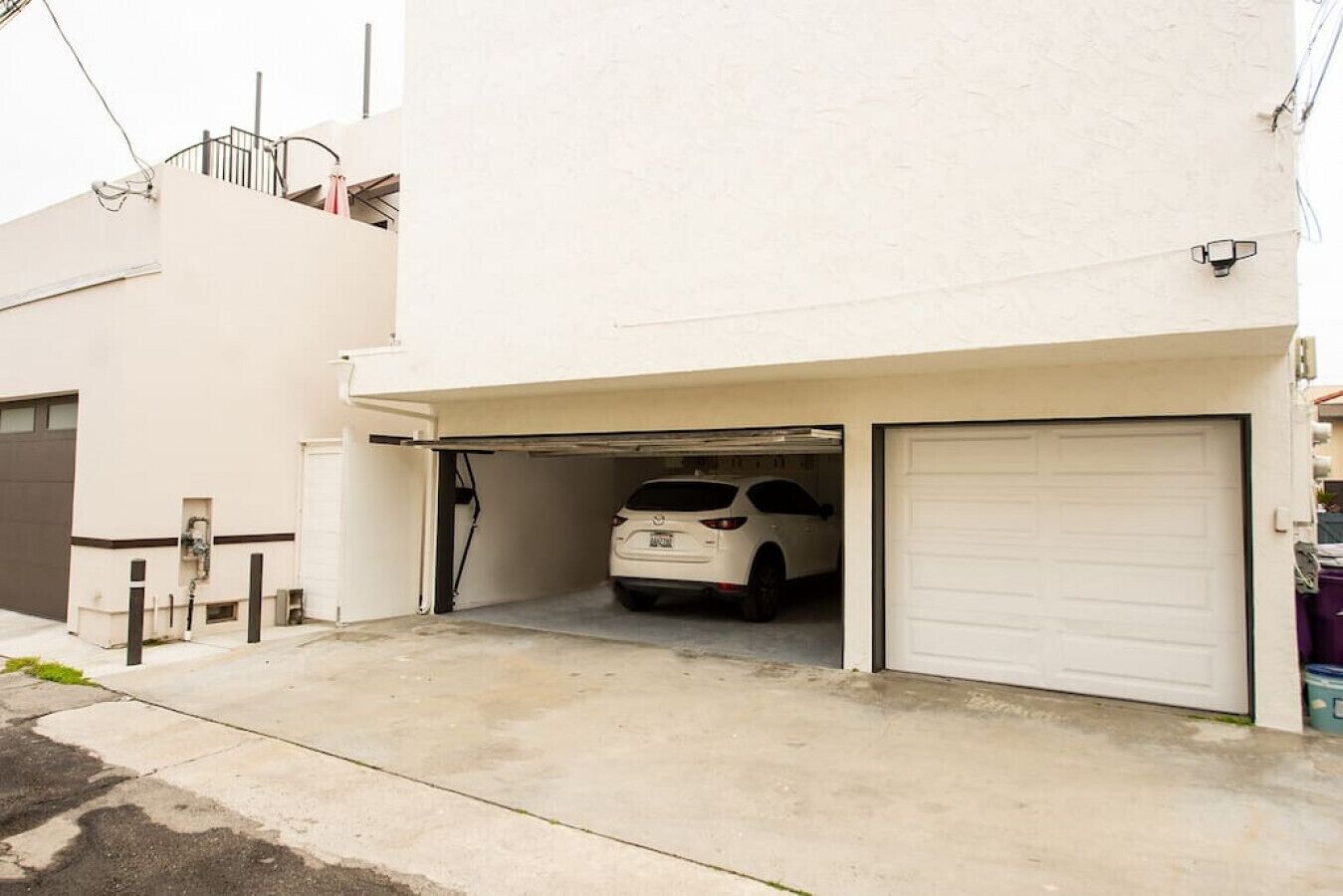 A single-story building with a white exterior, a garage with a white door, and a parked white car.