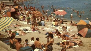 Ein voller Strand mit Menschen, die sich sonnen und schwimmen.
