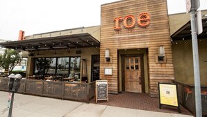Ein Restaurant mit einer Holzfassade und dem Schriftzug 'roe' über dem Eingang.