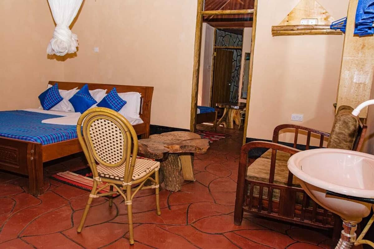 Un dormitorio con cama, una silla, una mesita y un lavamanos.