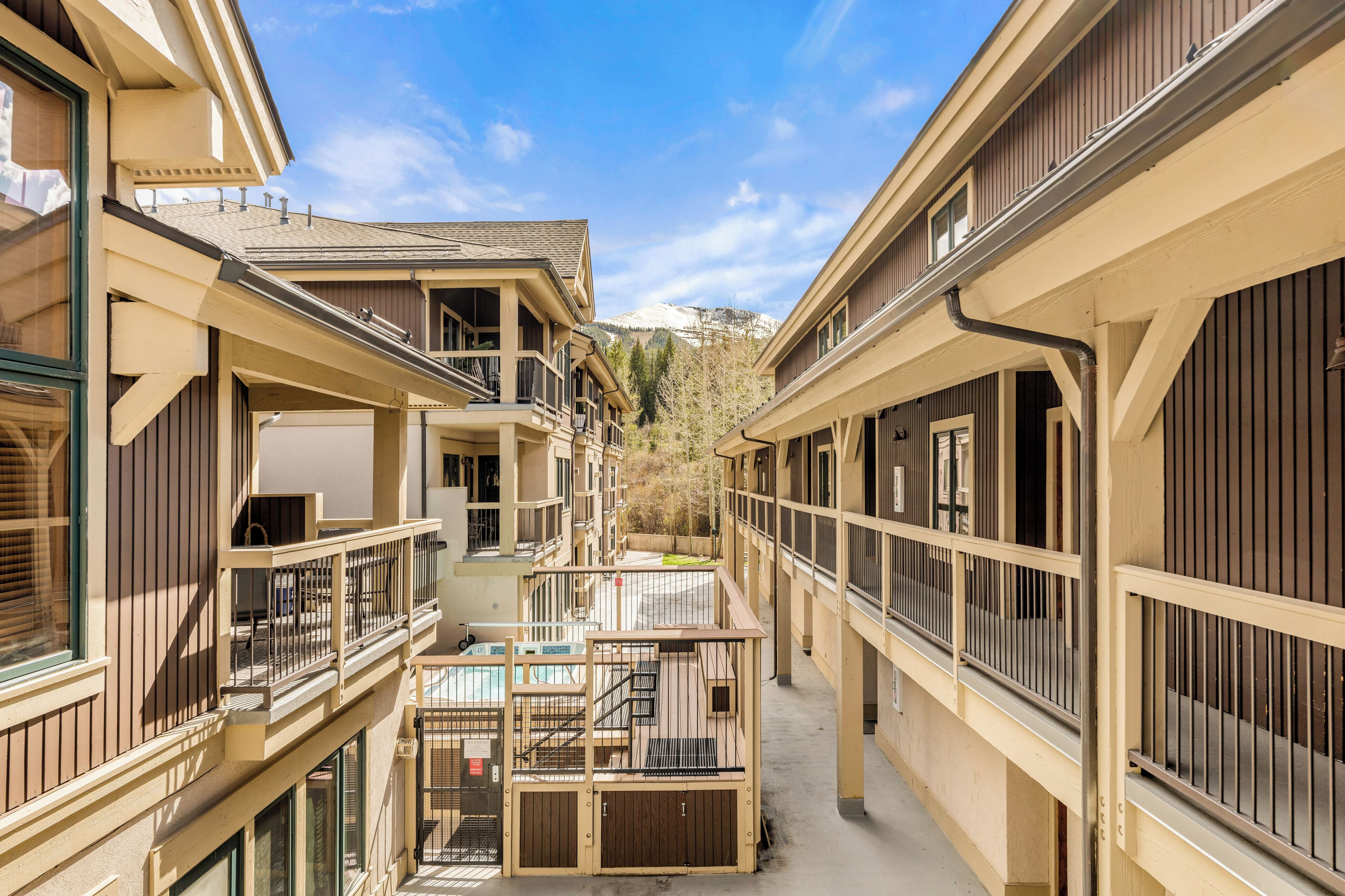 A multi-story hotel with balconies, a central courtyard, and a mountain view.