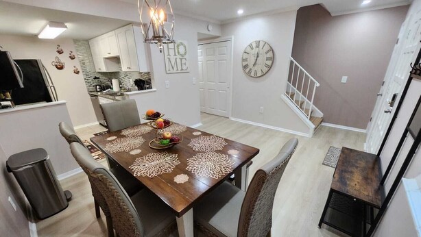 Un comedor con mesa de madera, sillas de mimbre y un centro de mesa con frutas.