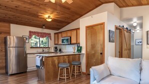 Una cocina con armarios de madera, un refrigerador de acero inoxidable, un microondas y una barra con taburetes.
