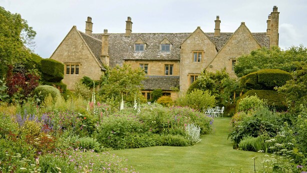 A historic stone building with a well-maintained garden and a clear pathway leading to the entrance.