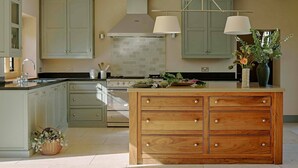 A modern kitchen with a central island, wooden cabinets, a stove, and a hanging light fixture.