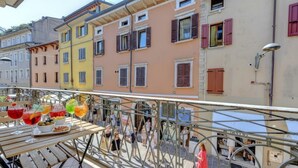 Un balcón con mesa lista para comer, con vista a edificios coloridos con contraventanas.