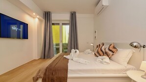 Habitación de hotel con cama, televisor montado en la pared, ventana con cortinas y vistas al exterior.