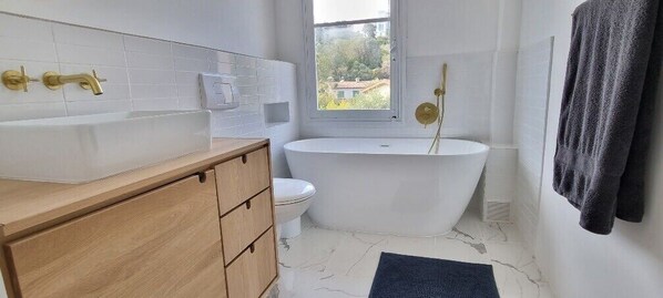 Une salle de bain moderne avec une baignoire sur pieds, des toilettes et un meuble-lavabo avec un évier.