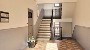 A hallway with a staircase, a potted plant, and a mail slot on the wall. - Bright Appartment, perfect location (Saint-Jean-Cap-Ferrat)