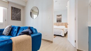 A modern room with a blue sofa, a mirror, and a bed with white bedding. - Casa Love 3A (Panama City)