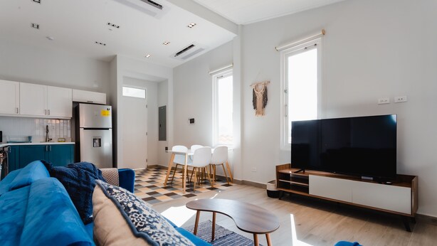 A modern living room with a sofa, a TV, and a dining area with chairs and a table. - Casa Love 3A (Panama City)