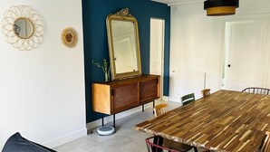 A dining area with a wooden table, chairs, a sofa, a cabinet, and a mirror.