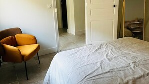 A bedroom with a bed, a chair, and a wardrobe.