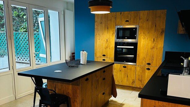 A modern kitchen with wooden cabinets, a black countertop, and a built-in oven.